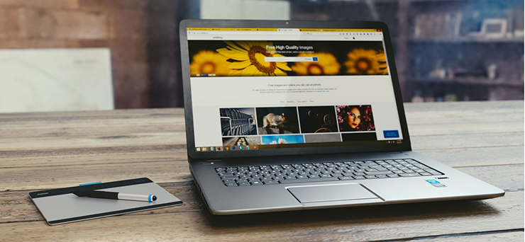 Ein aufgeklappter Laptop steht auf einem massiven Holztisch. Auf seinem Bildschirm ist eine Website zu sehen.